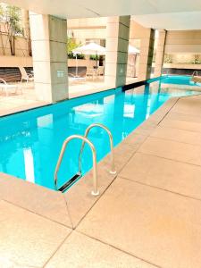 a swimming pool with blue water in a building at São Paulo Moema Times Square - Suite LUXO in Sao Paulo