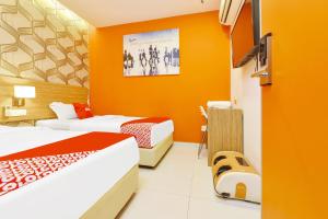 two beds in a room with orange walls at Super OYO 90512 Sovotel Kelana Jaya 79 in Petaling Jaya