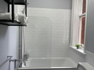 a white bathroom with a tub and a window at Airy Apartment Sefton Park in Liverpool