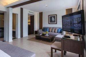 Cape Panwa Hotel Phuket في شاطئ بنوا: غرفة معيشة بها أريكة وتلفزيون