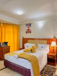 Schlafzimmer mit einem großen Bett und gelben Vorhängen in der Unterkunft LEYSHOF HOTEL in Mwanza