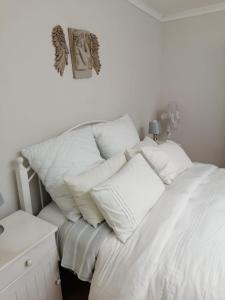 a white bed with white pillows on top of it at Feet Up Cottage in Somerset West