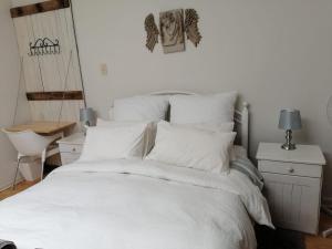a white bed with white sheets and pillows at Feet Up Cottage in Somerset West