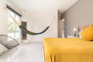 a bedroom with a yellow bed and a hammock on the wall at VISTA Departamento privado dos habitaciones Cancún in Cancún