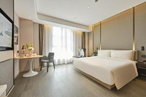 a hotel room with a large white bed and a desk at Atour Hotel Shanghai Songjiang Sports Center in Shanghai