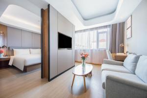une chambre d'hôtel avec un lit, un canapé et une table dans l'établissement Atour X Hotel Yantai Penglai Pavilion, à Penglai