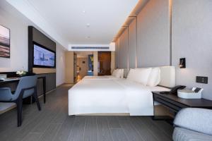 um quarto de hotel com uma grande cama branca e uma secretária em Atour Hotel Xiaolan Zhongshan em Zhongshan