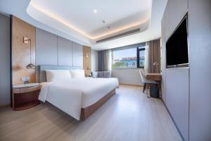 Pokój hotelowy z dużym łóżkiem i telewizorem w obiekcie Atour X Hotel Yantai Penglai Pavilion w mieście Penglai