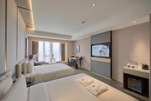 um quarto de hotel com duas camas e uma televisão em Atour Hotel Taixing Municipal Government Drum Tower Xintiandi em Taizhou