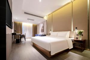 Pokój hotelowy z dużym białym łóżkiem i biurkiem w obiekcie Atour Hotel Wuhan Guanshan Avenue Guanggu Software Park w mieście Wuhan