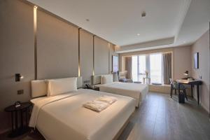 a hotel room with two beds and a desk at Atour Hotel Taixing Municipal Government Drum Tower Xintiandi in Taizhou