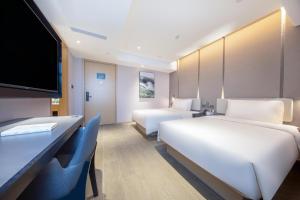a hotel room with two beds and a flat screen tv at Atour Hotel Bohai International Plaza Binzhou in Binzhou