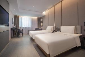 a hotel room with two beds and a table at Atour Hotel Nantong Jinsha in Nantong