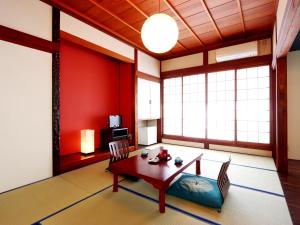 sala de estar con paredes rojas, mesa y sillas en 富山県 よしのや旅館, en Nanto