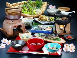 una mesa cubierta con tazones y platos de comida en 富山県 よしのや旅館, en Nanto