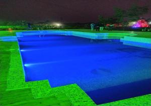 ボルプルにあるSTAYMAKER Gharana Resortの夜間の青い照明が灯るスイミングプール