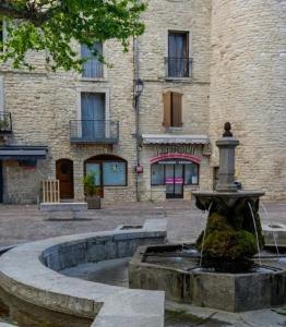 einem Brunnen vor einem Gebäude in der Unterkunft Joli studio Les Hibiscus du Pic Saint Loup in Saint-Martin-de-Londres