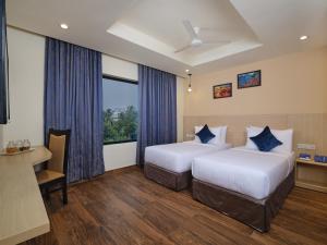 a hotel room with two beds and a desk at Essentia Premier Hotel Chennai OMR in Chennai