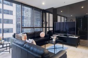 a living room with a couch and a flat screen tv at Castlereagh - 2BR Sydney CBD Views Hyde Park Families & Groups in Sydney