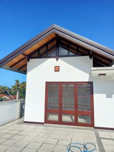 un bâtiment blanc avec une porte de garage rouge dans l'établissement Villa Suyara Rooftop,,,, à Panadura