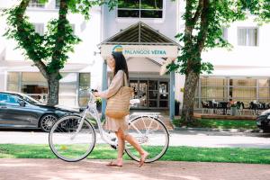 a woman walking a bike on a sidewalk at Palangos Vetra in Palanga