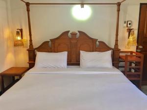 - une chambre avec un grand lit blanc et une tête de lit en bois dans l'établissement The Creek Garden Resort Huainamrin ห้วยนำ้ริน, à Mae Hong Son