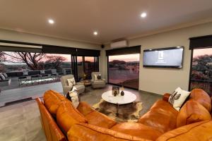 a living room with couches and a flat screen tv at Leeuwkop Hunting Safaris in Kimberley