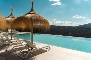 una piscina con sedie e ombrelloni di paglia di Hoteles Desconecta2 a Monesterio