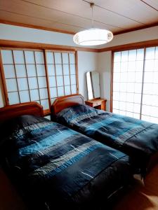 a bedroom with a large bed in a room with windows at Homestay Intimo Amigo in Tokyo
