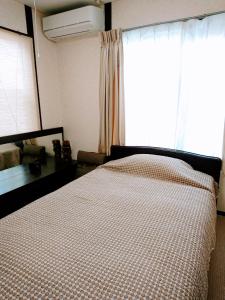 a bedroom with a bed and a window with a bedspread at Homestay Intimo Amigo in Tokyo