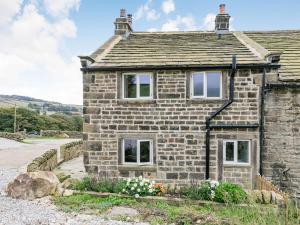 een oud stenen huis aan de kant van een weg bij Spinners Cottage in Keighley