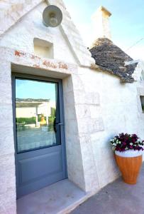 a door of a house with a flower pot next to it at Trullo La chicca della valle in Cisternino