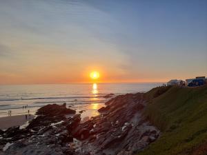 a sunset on the beach with the sun setting over the ocean at Tregella Guest House in Newquay