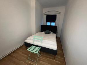 ein kleines Schlafzimmer mit einem Bett und einem grünen Stuhl in der Unterkunft Hagmann's Altstadt Appartement in Krems an der Donau