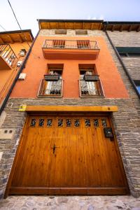 um edifício com uma porta de madeira e três janelas em Cal Muntanyà em Puigcerdà