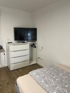 um quarto com uma televisão de ecrã plano numa cómoda branca em Gemütliche 1-Zimmer Wohnung mit eigenem Eingang em Wesseling