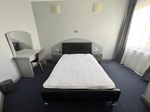 1 dormitorio con cama, escritorio y espejo en Motel Carmen, en Baia Mare