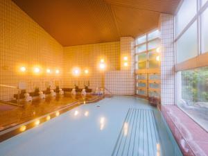 a swimming pool in a large room with a large window at KAMENOI HOTEL Yamato Heguri in Heguri