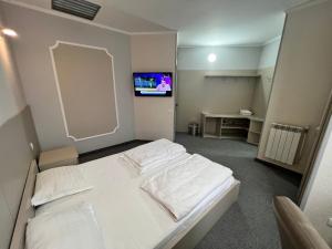 a bedroom with a white bed and a flat screen tv at Motel Carmen in Baia Mare