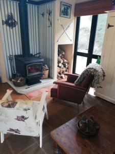 Una sala de estar con un sofá y una chimenea. en Cosy Country Cottage - Outdoor Pizza Oven - Rural Setting on 4 Acres, en Raetihi