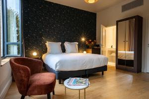 - une chambre avec un lit, une chaise et une table dans l'établissement L'Invitation au Voyage Hôtel- Espace Bien-être - Bar Lounge, à Honfleur