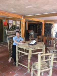 une femme assise à une table en bois dans une pièce dans l'établissement Bee lucky homestay cat ba Island, à Xuan Dam