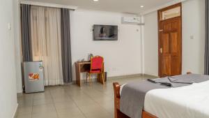 um quarto com uma cama, uma secretária e uma mesa em Whirlspring Hotel em Kisumu