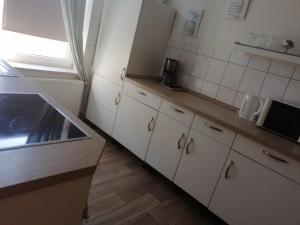 eine Küche mit weißen Schränken, einem Waschbecken und einem Fenster in der Unterkunft Ferienwohnung Poehlmann in Plauen