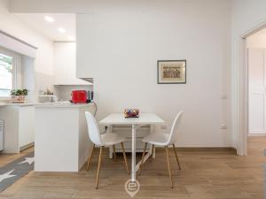 a white kitchen with a white table and chairs at Casa Aura in Oristano