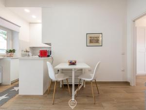 a white kitchen with a white table and chairs at Casa Aura - City Centre in Oristano