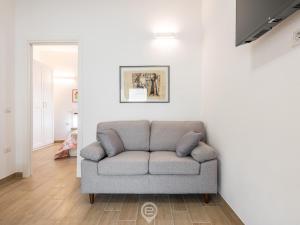 Casa Aura - City Centre في أوريستانو: أريكة في غرفة المعيشة بجدران بيضاء