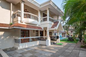 a large white house with a courtyard and palm trees at 5BHK Villa Calangute Phase 2, just 2 Min walk to Calangute Beach in Arpora
