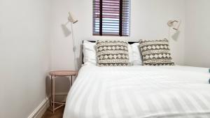 a bedroom with a white bed with pillows and a window at Thompson Apartments by Switchback Stays in Cardiff