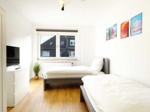 a white bedroom with two beds and a television at Cosy & Central-Apartments in Gelsenkirchen in Gelsenkirchen